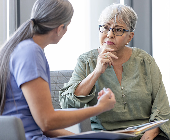 The senior adult woman listens carefully as the caregiver explains the program.